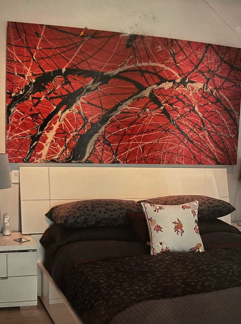 Red abstract painting above a bed in a bedroom