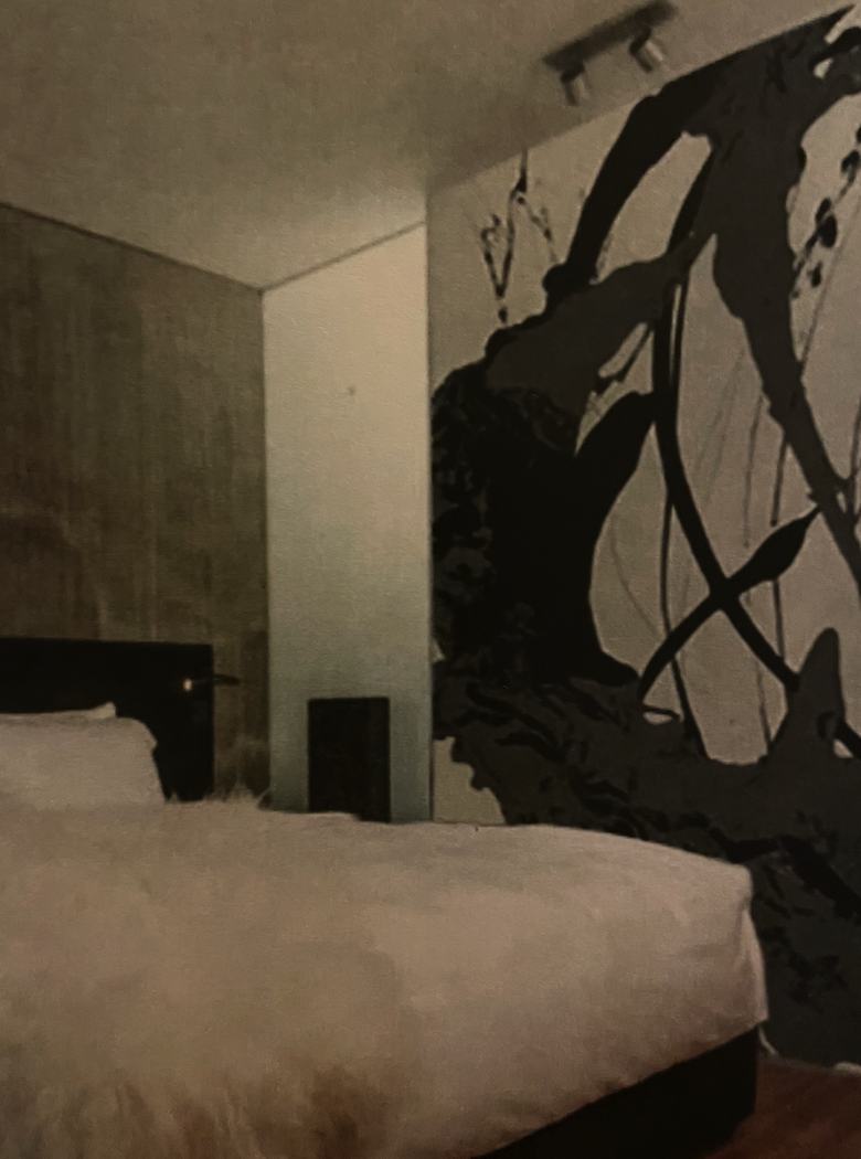 Black and white mural-scale work beside a bed